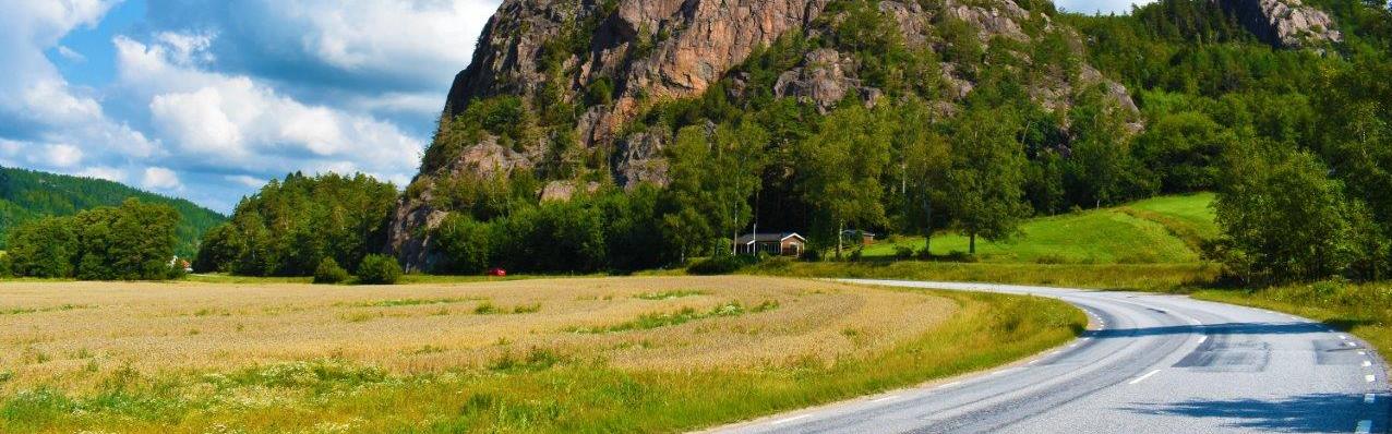 Ett stort berg vid en bilväg och åkermark i Bärfendal